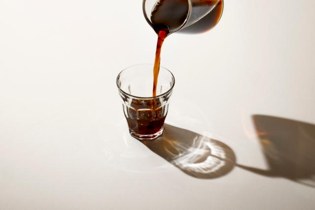 Sort kaffe hældes i et glas