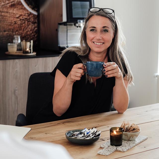 kvinde drikker kaffe og kan læse i bki nyhedbrev