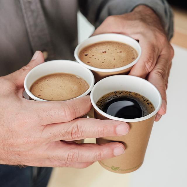 Mand holder tre engsangskrus med kaffe