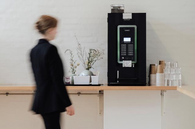 kvinde går hen til animo instant kaffemaskine på arbejdet 